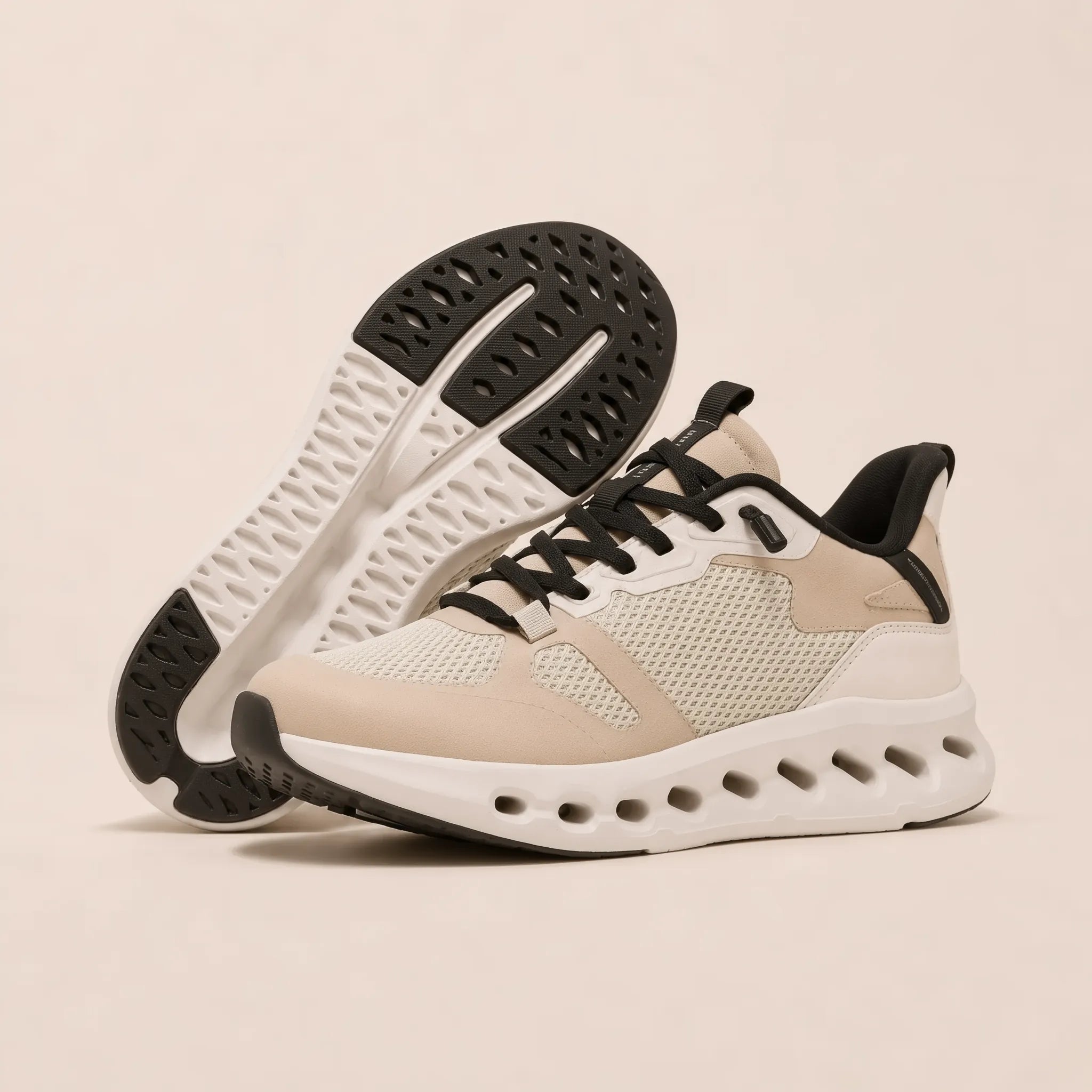 A pair of low-top athletic sneakers in beige and white with black accents, including the laces, collar lining, and outsole. One shoe is shown from the side profile, and the other is positioned behind it to display the textured black and white sole.